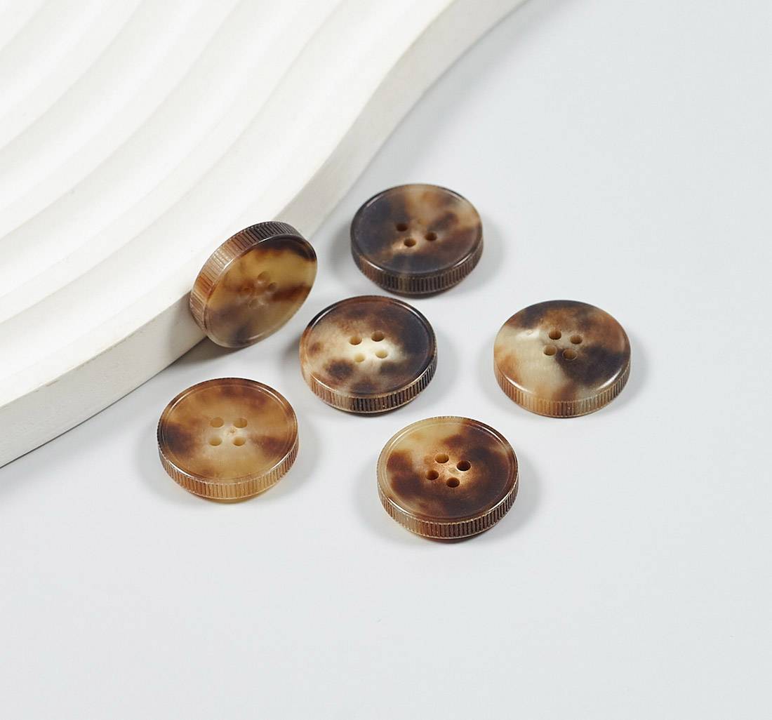 Пуговица на 4 прокола из натурального рога, блестящая, рифленый гурт. Цвет светло-коричневый в наличии