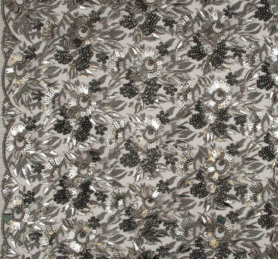Ткань Кружево вышитое, декорированное цветами из бисера, металлизированными пайетками и фигурными элементами. Основа- кружево из искусственного шелка. Цвет основы- пепельный, цвет вышивки- оружейная сталь в наличии